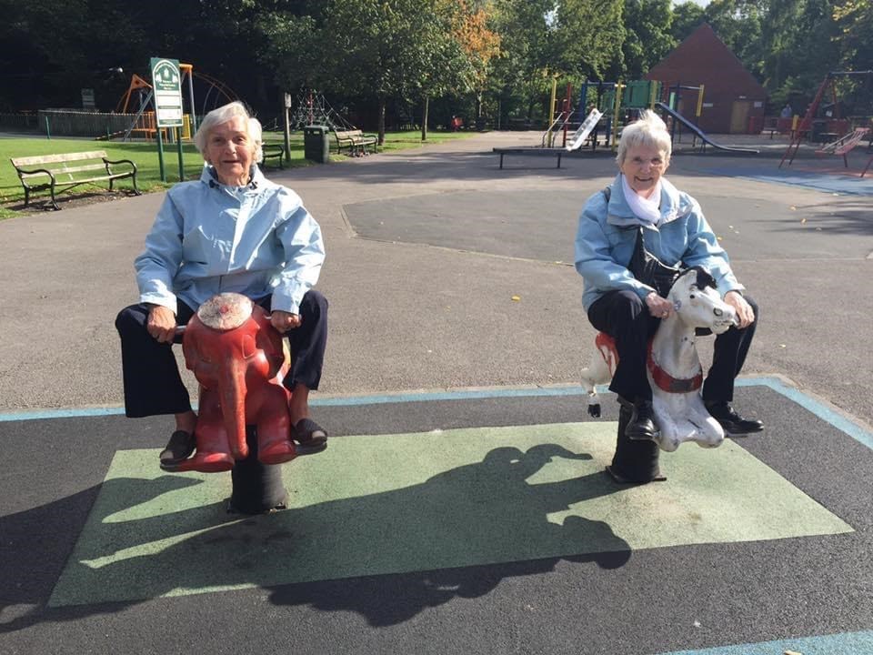 Women riding on rocking horses in a playground