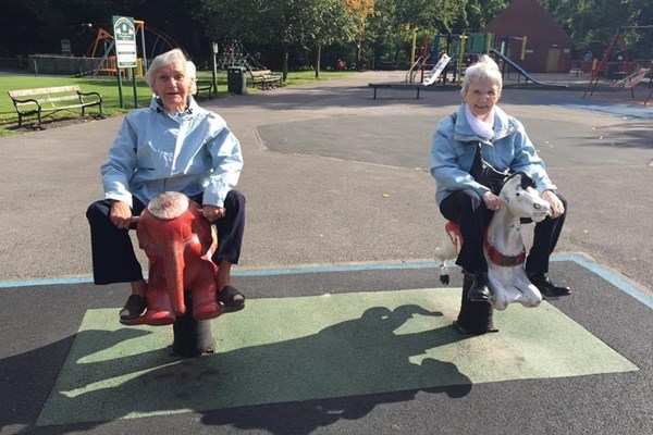 Women riding on rocking horses in a playground