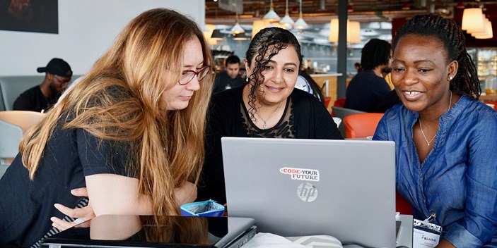 An image of three women sat together working at a laptop