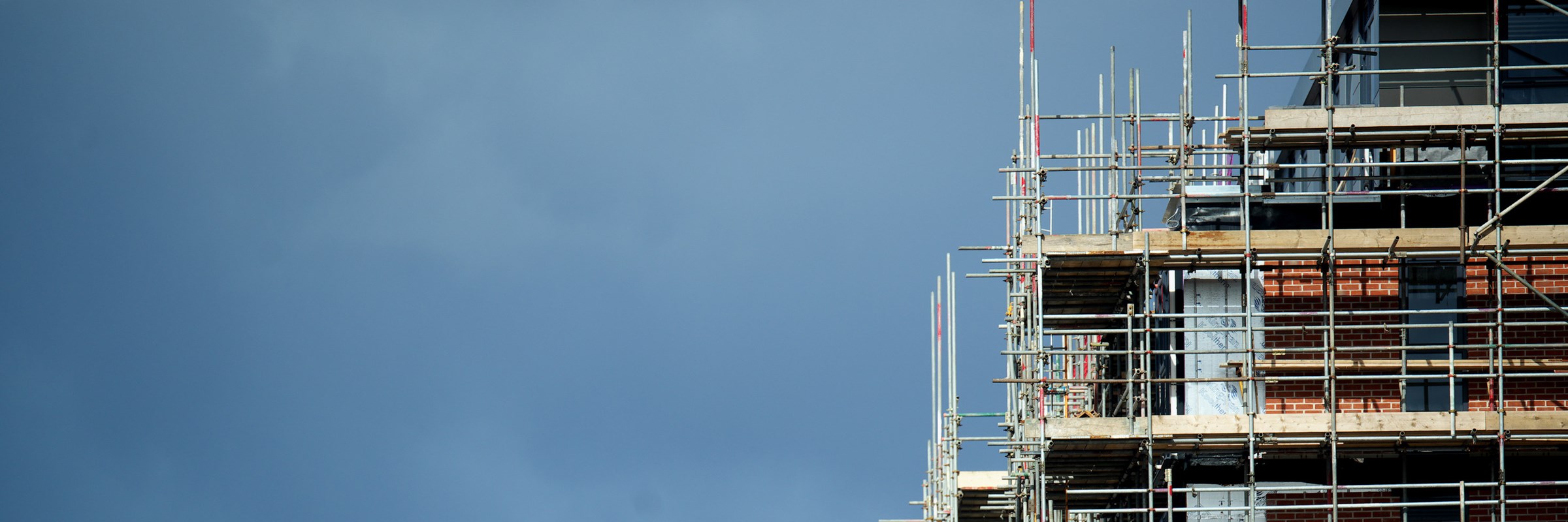 Scaffolding of tall tower with clouds and sky in background