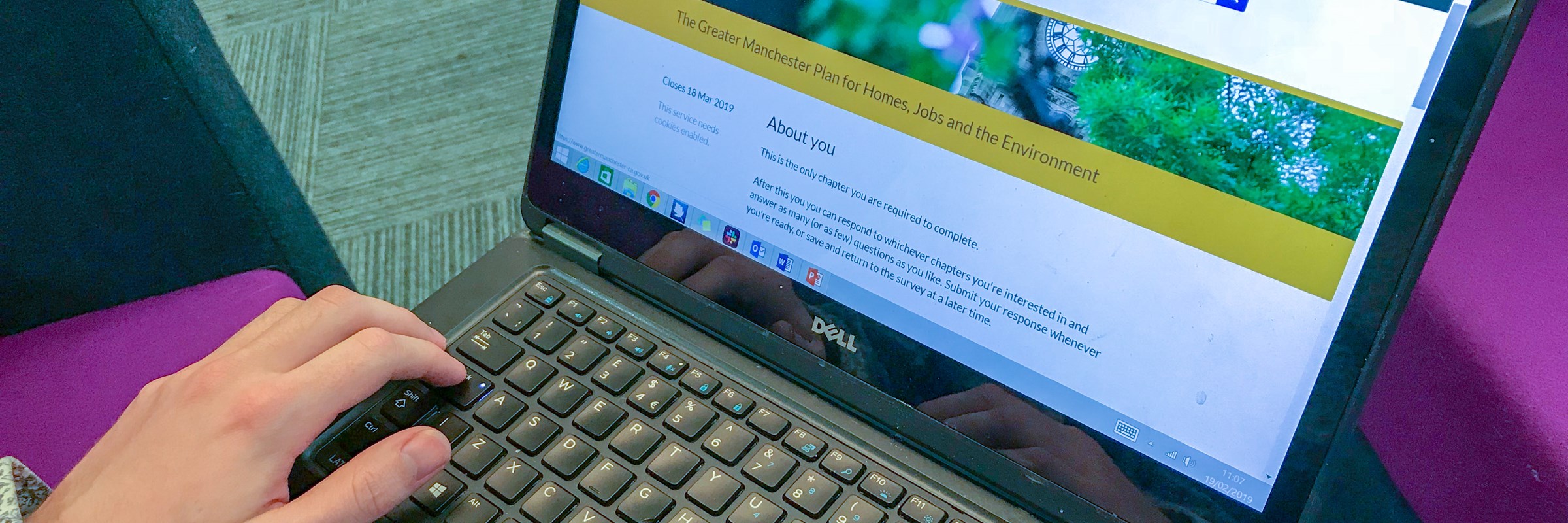 A person presumed to be looking at a web page on a laptop. Their two hands can be seen resting on the laptop keyboard with the screen showing a webpage that includes the words GMCA.