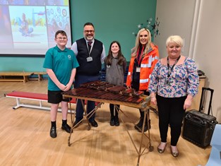 Suez staff stands with head boy and girl and two teachers as they present the donated xylophone