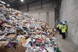 Close up of a pile of paper and card with group of visitors in hi-vis jackets standing in the background