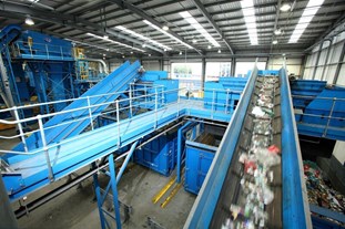 Mixed recycling speeds past on a conveyer belt inside the Materials Recovery Facility