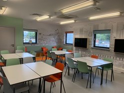 The classroom at the education centre, with tables and chairs, large television screens and decorative wallpaper