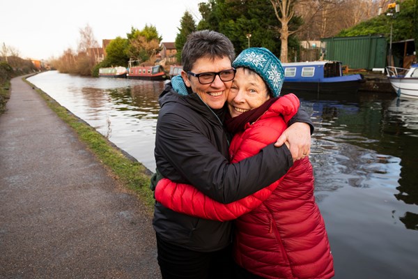 Two people hugging by a canal.