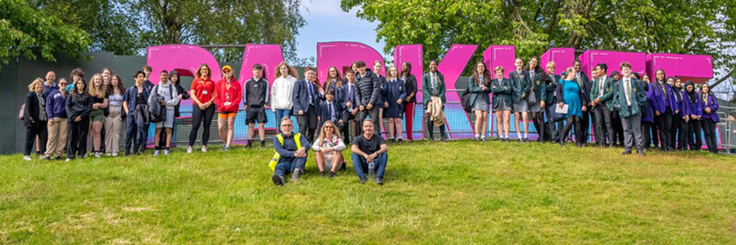 School pupils, teachers, Sacha Lord and Parklife team in front of Parklife sign at the festival