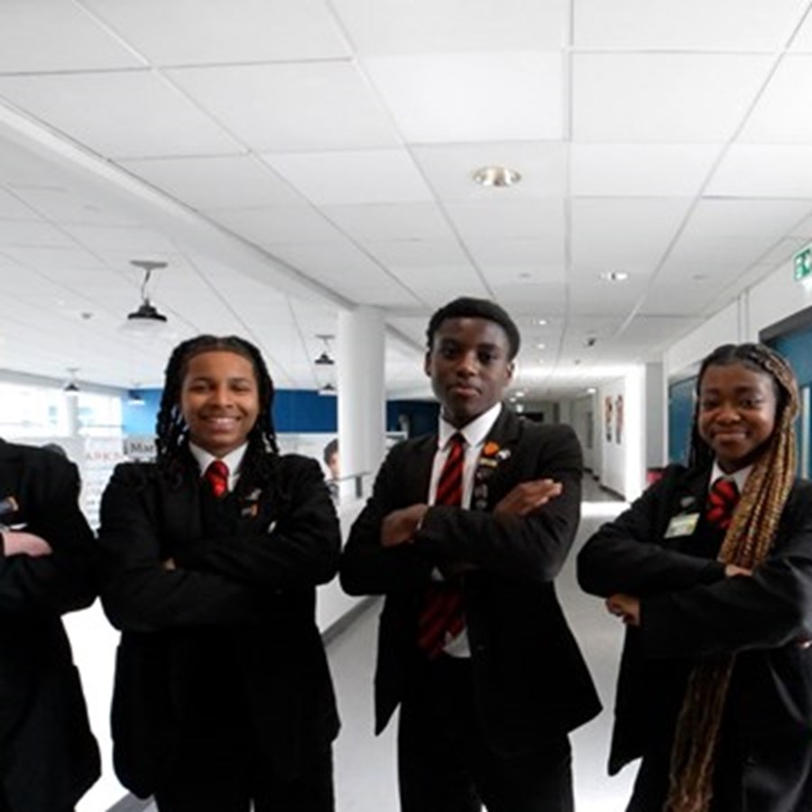 Five school pupils stood in uniform in a school hallway