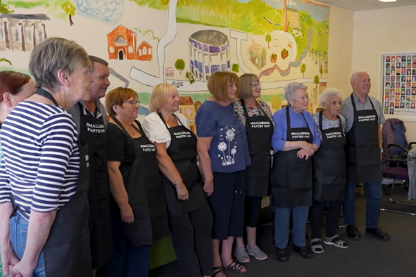 Group of older people in aprons standing up.