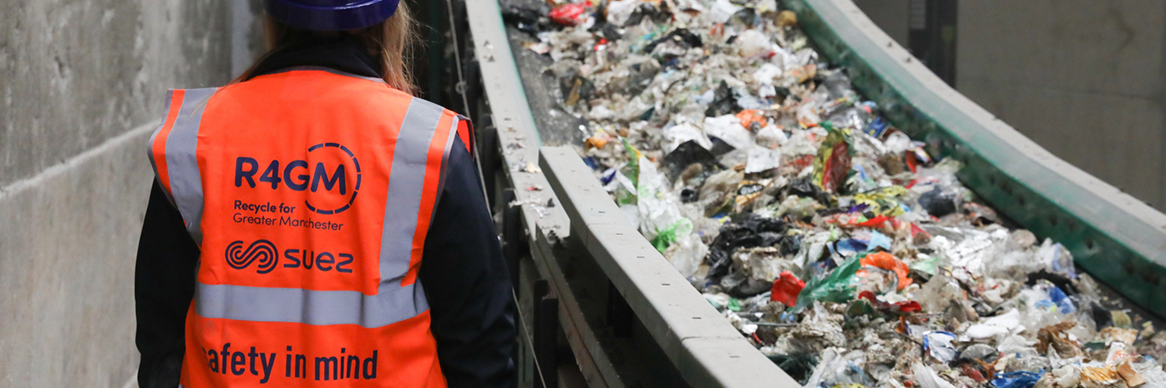 Waste facility worker overlooking a stream of waste on a conveyor belt