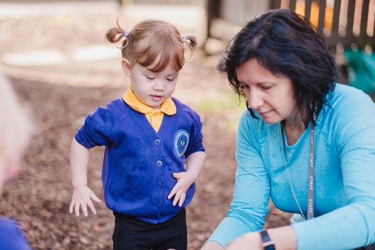 teacher playing outside with young child