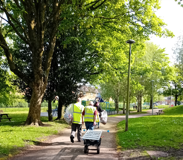 People in high-vis jackets litter picking in a park.