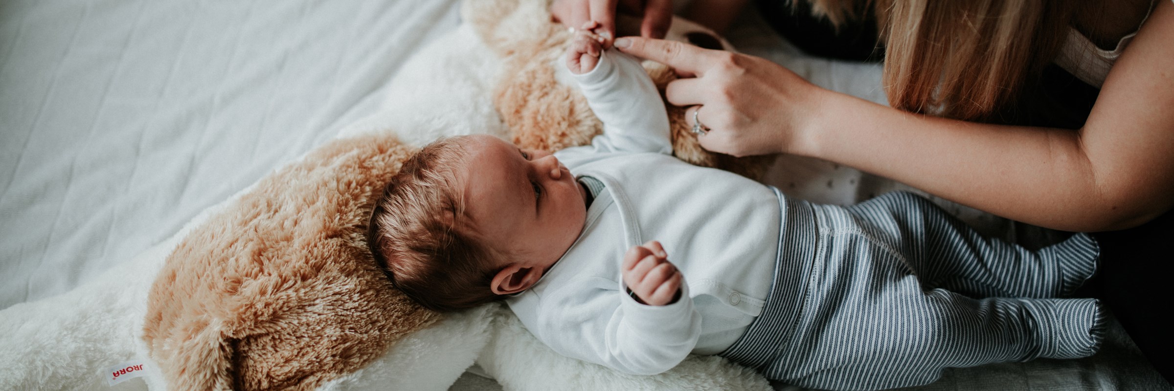 Man and woman tickling the hands of young baby